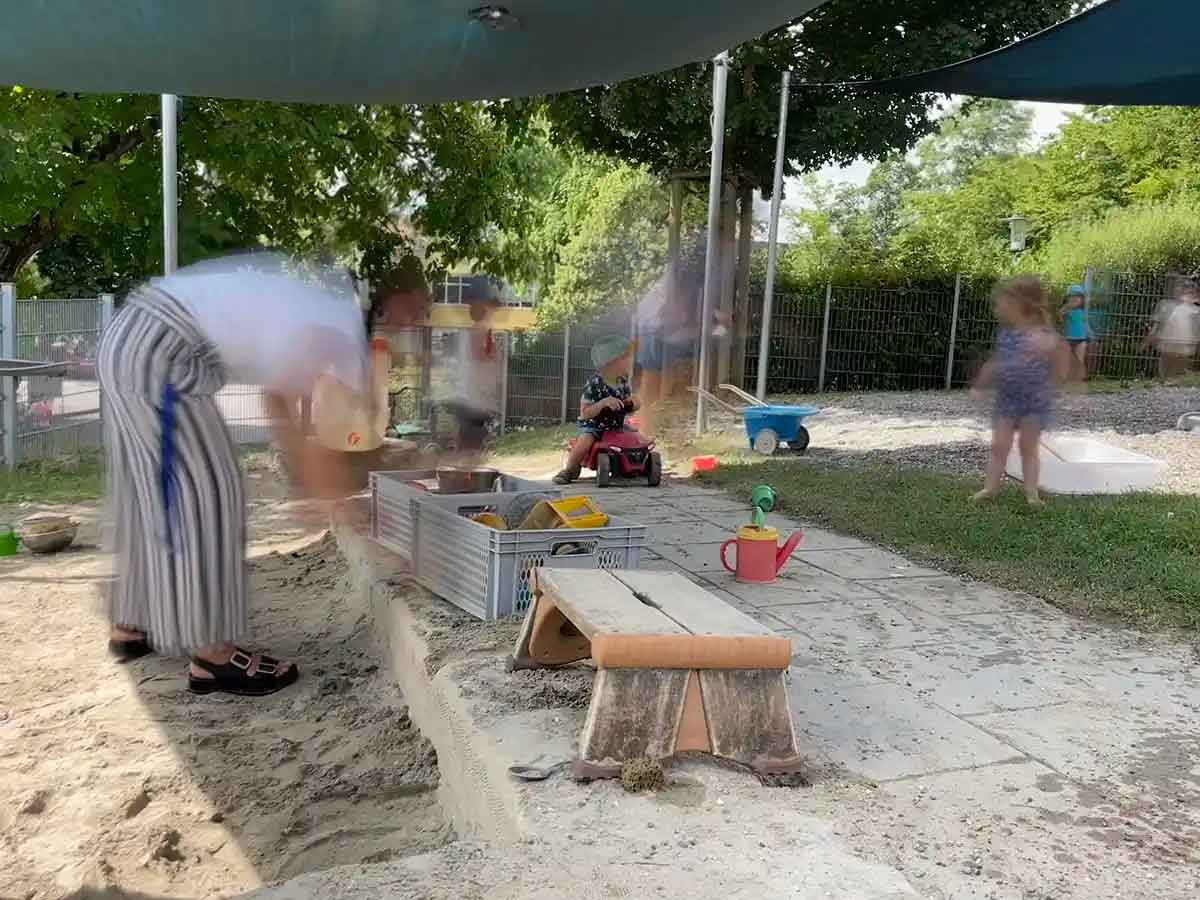 Im Kinderhaus St. Verena in Konstanz: Im Sandkasten räumt eine Erzieherin Spielsachen in Kisten. Im Hintergrund spielen Kinder