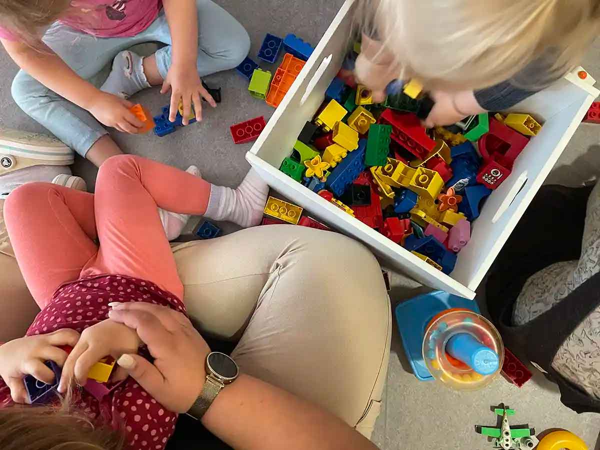 Eine Erzieherin spielt mit drei Mädchen Lego in der Krippe Stromerle in Konstanz