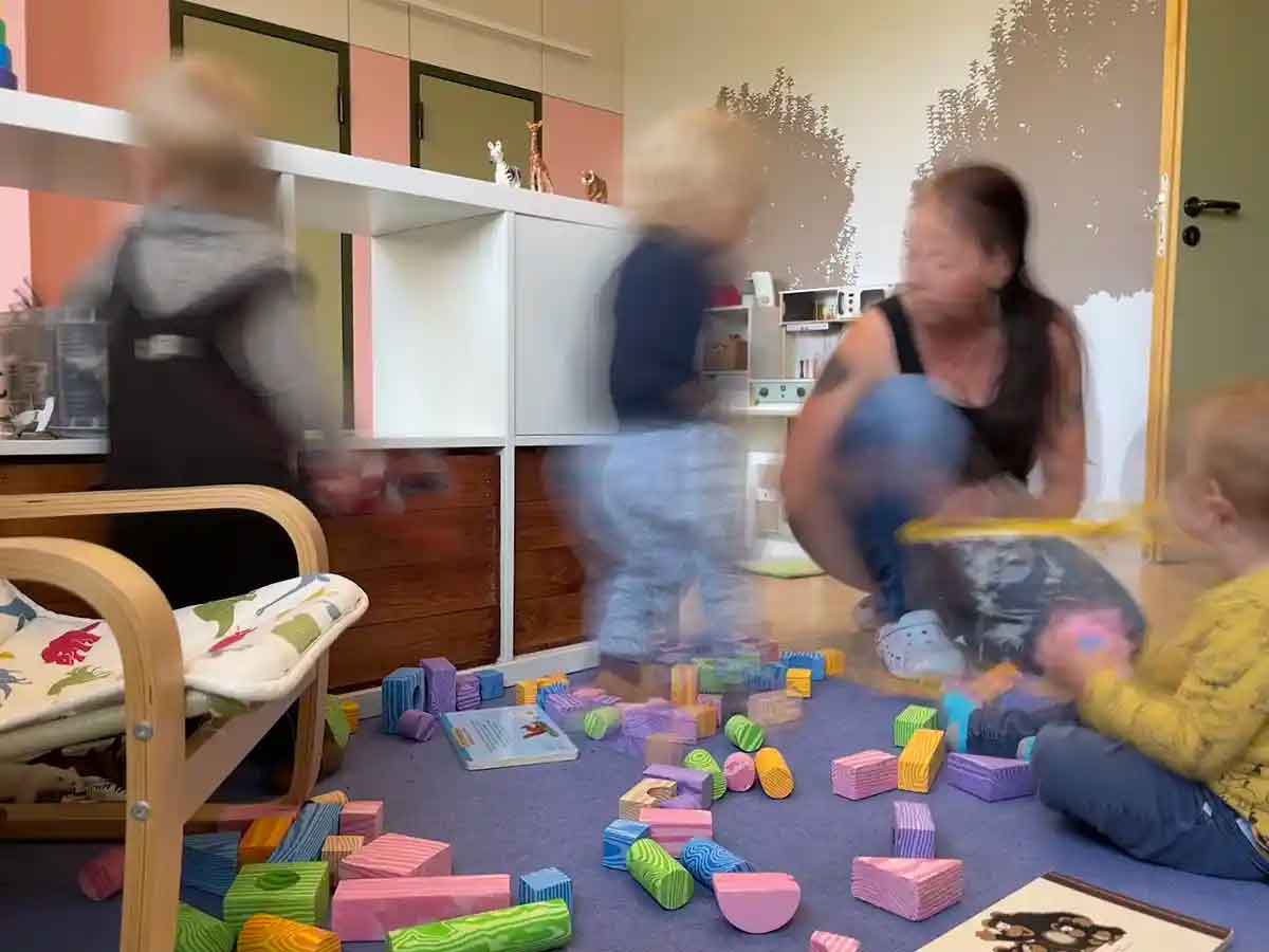 In der Krippe Stromerle spielt eine Erzieherin mit Kindern und Bausteinen.