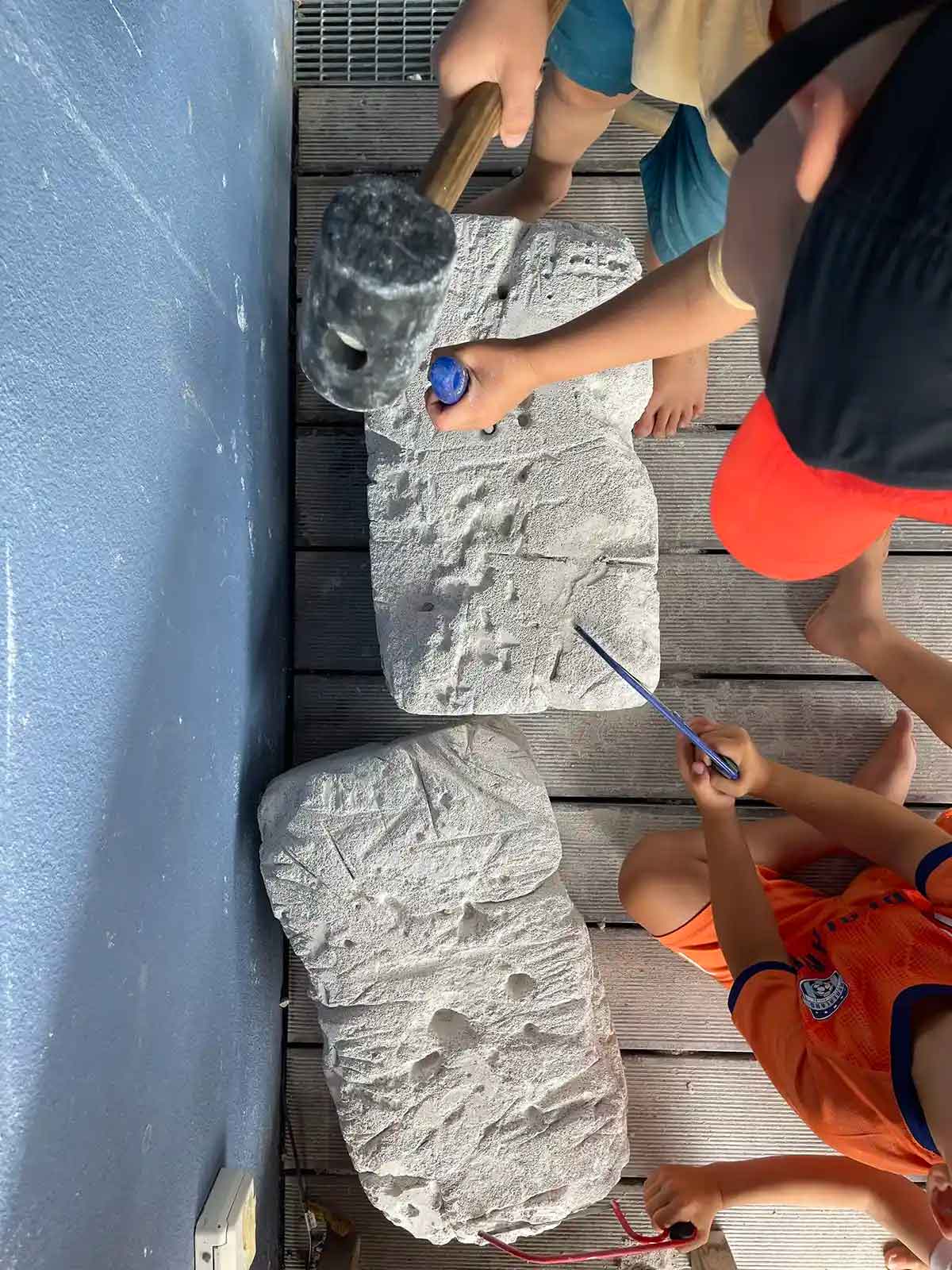 Kinder klopfen mit einem Gummihammer und einem Meißel auf einen Stein in der Konstanzer Kita "Pädagogischer Mittagstisch"